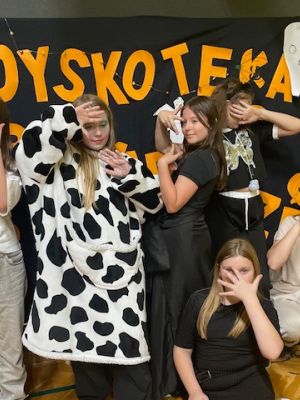 Uczestnicy dyskoteki robią sobie zdjęcie na ściance.