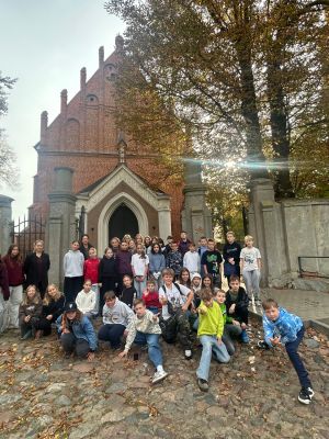 Uczniowie w pamiątkowym zdjęciu na tle kościoła w Mszczonowie.