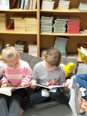 Dzieci w bibliotece szkolnej czytają bajki i baśnie. 