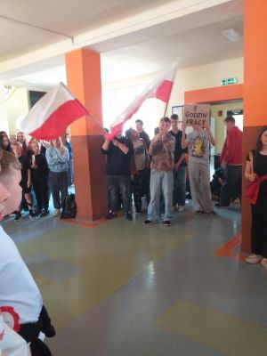  Inscenizacja manifestacji robotniczej. Uczniowie klas &oacute;smych skandują hasła i machają flagami Polski i UE.
