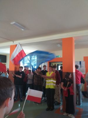  Inscenizacja manifestacji robotniczej. Uczniowie klas &oacute;smych skandują hasła i machają flagami Polski i UE.