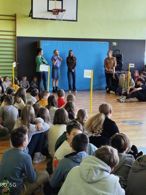 Nauczycielka prezentuje uczennicę, opowiadając o jej sukcesie. 