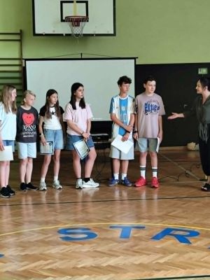 Nauczyciel prezentuje uczni&oacute;w, kt&oacute;rzy uzyskali sukcesy w konkursach matematyczno-informatycznych