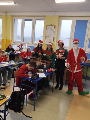 Uczniowie w świątecznych przebraniach rozdają mikołajkowe prezenty.