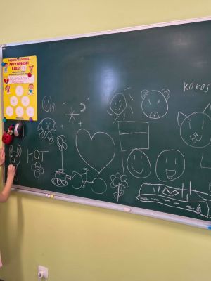 Z wizytą w szkole - zer&oacute;wkowicze rysują po tablicy.