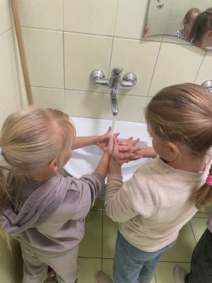 Uczennice ćwiczą prawidłowe mycie rąk w szkolnej łazience.