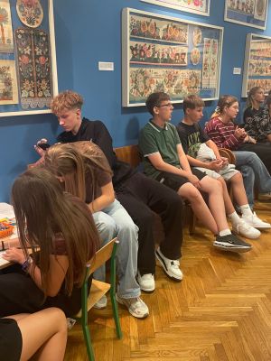 Grupa uczni&oacute;w odpoczywa podczas zwiedzania muzeum.
