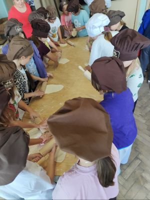 Podczas warsztat&oacute;w wypieku rogali świętomarcińskich uczniowie własnoręcznie wyrabiają i wałkują ciasto, poznając tajniki przygotowania tego wyjątkowego poznańskiego przysmaku.
